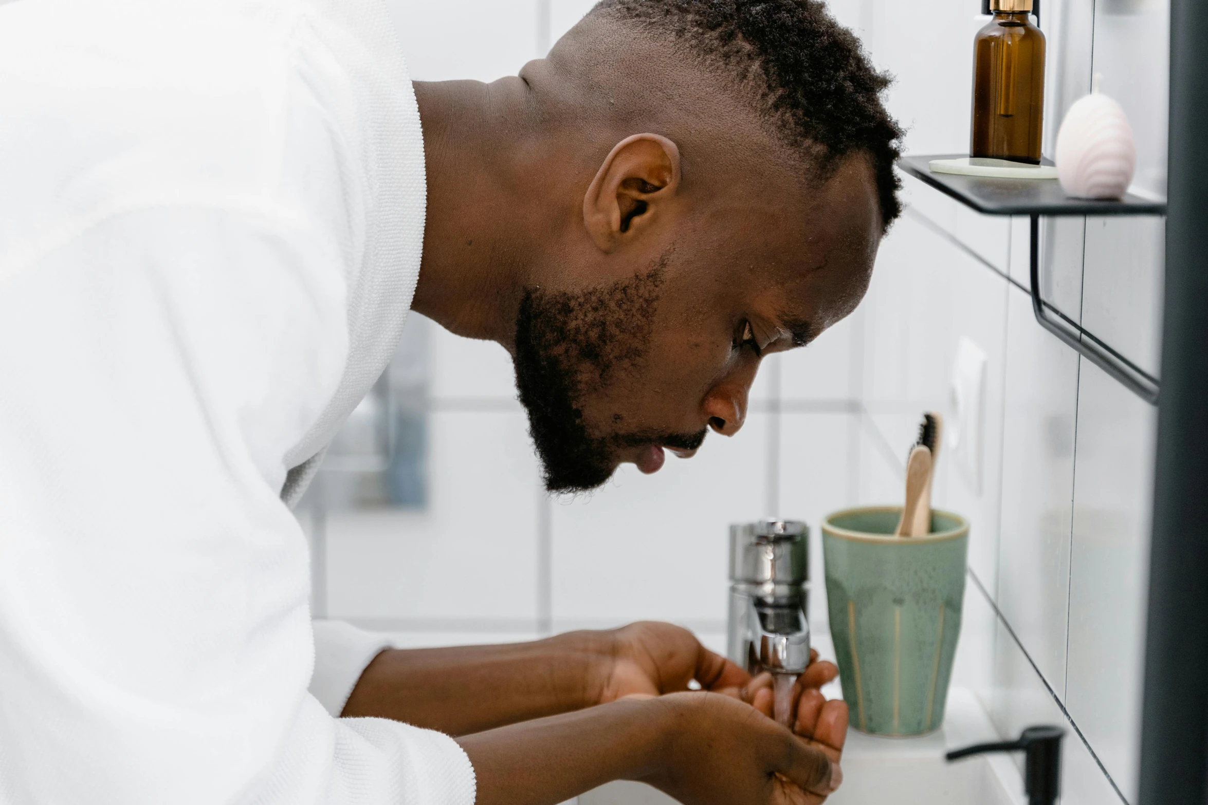 a male in a white shirt is checking soing on a sink