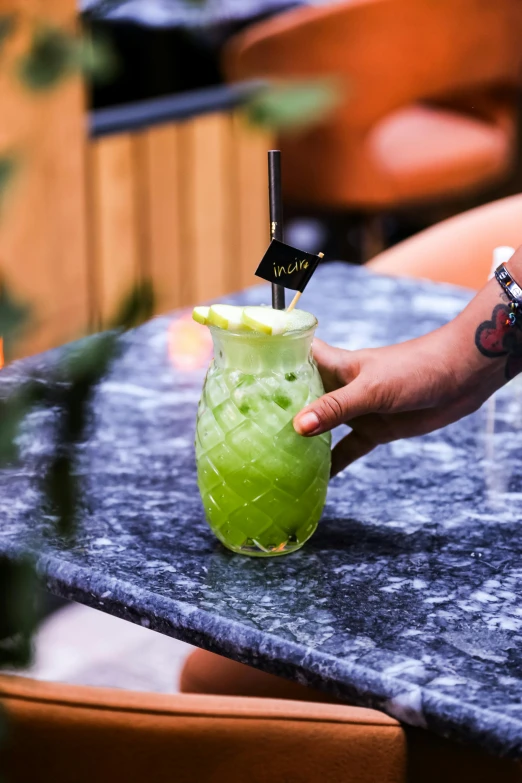 the green liquid in the glass is being poured