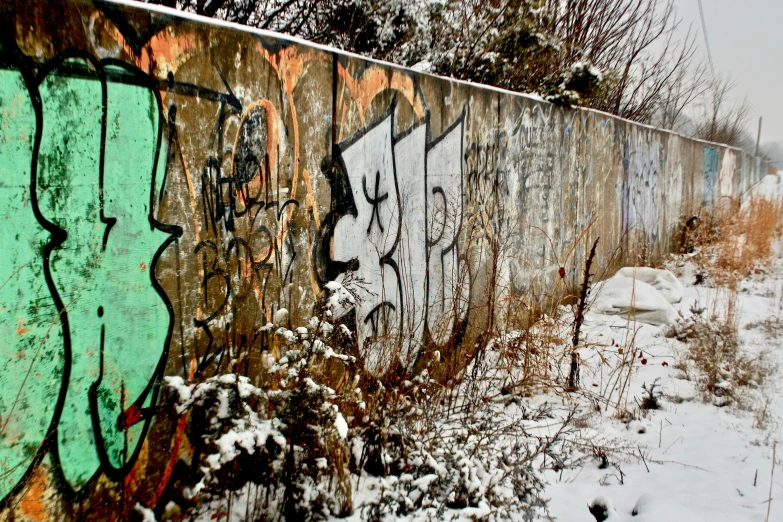 a wall covered in graffiti on the side of a road