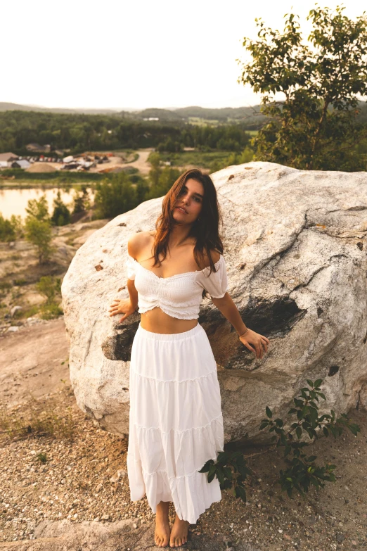 a woman is posing against the rocks at sunset