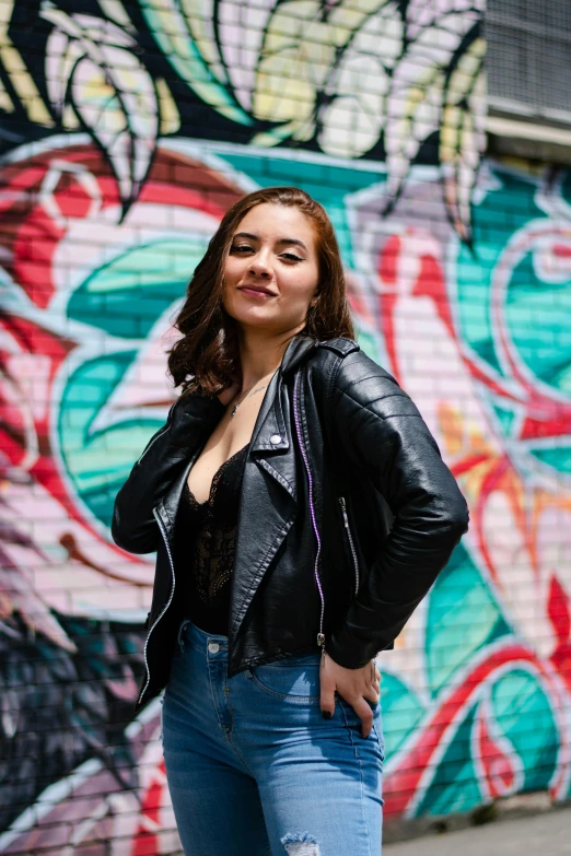 a woman is standing near a wall with flowers on it