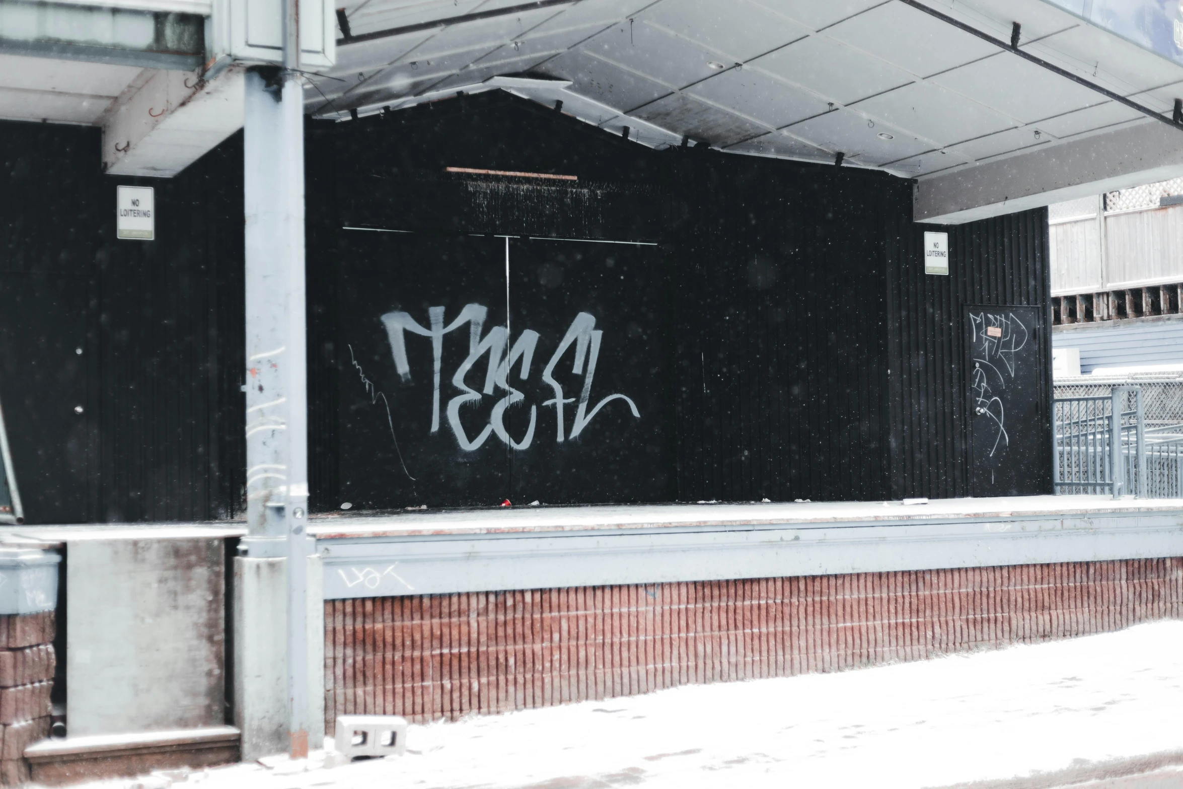 graffiti on a black wall, above a red brick wall