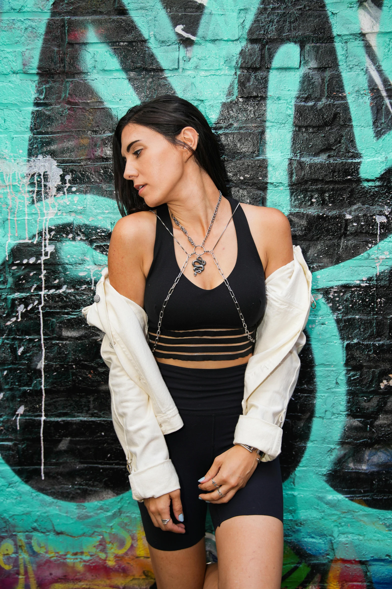 a woman in high - rise shorts is standing near graffiti