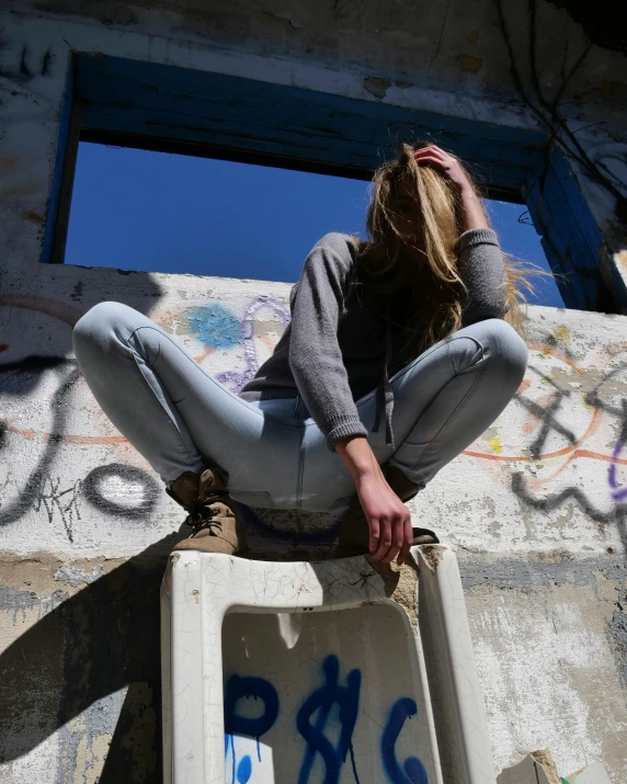 a woman is sitting in a concrete dumpster