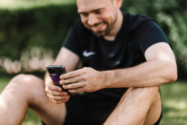 a man sitting on the ground looking at his cell phone