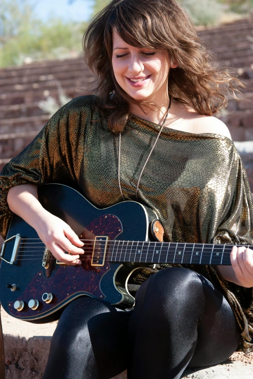 young woman with electric guitar outdoors in town