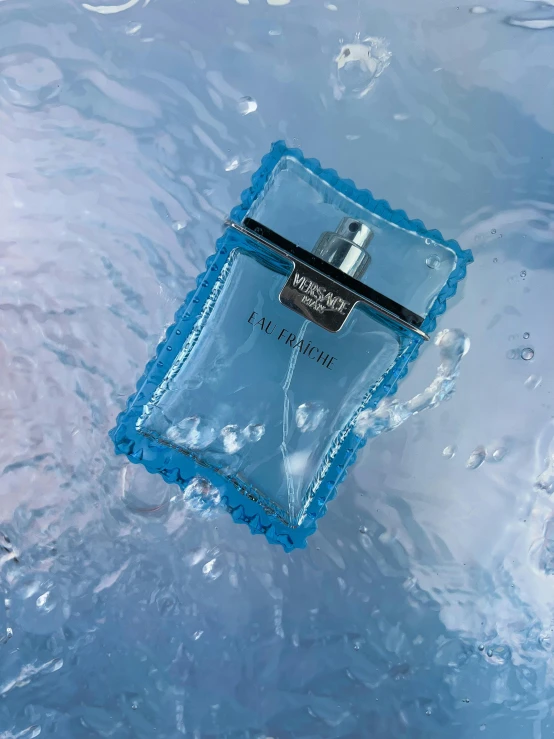 a blue perfume bottle sitting in a stream of water