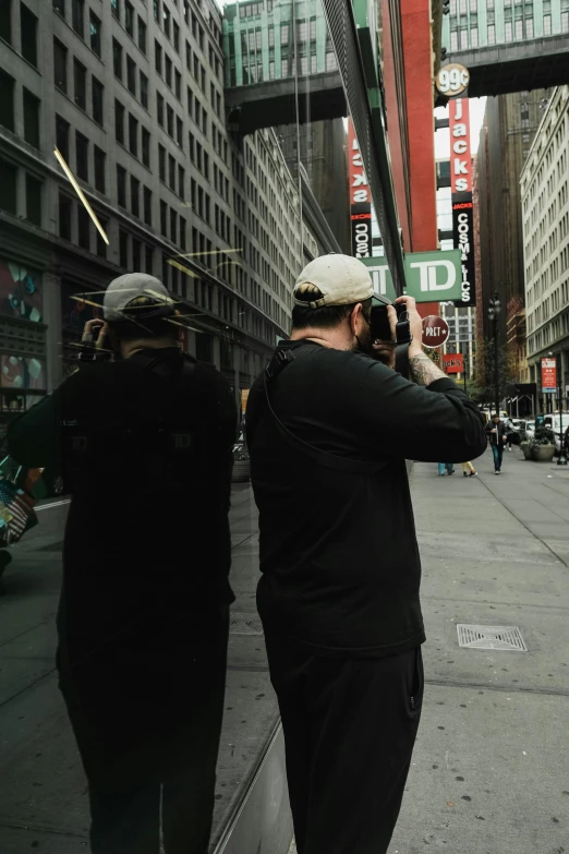 two people with hats are taking pictures down a sidewalk