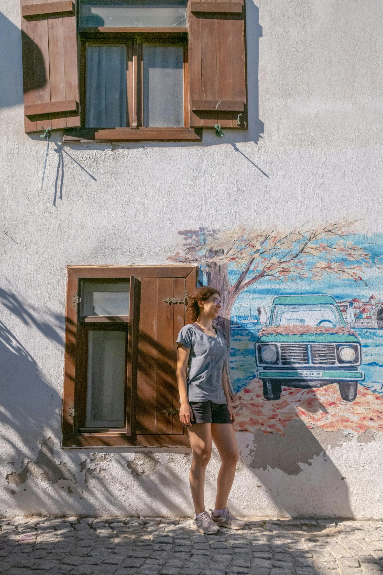 a woman stands in front of a mural on the side of a building