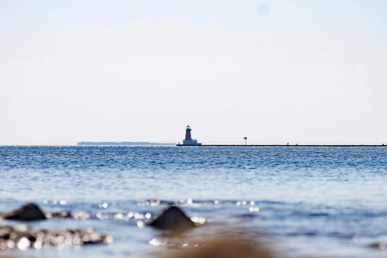 a lighthouse on the water near some rocks