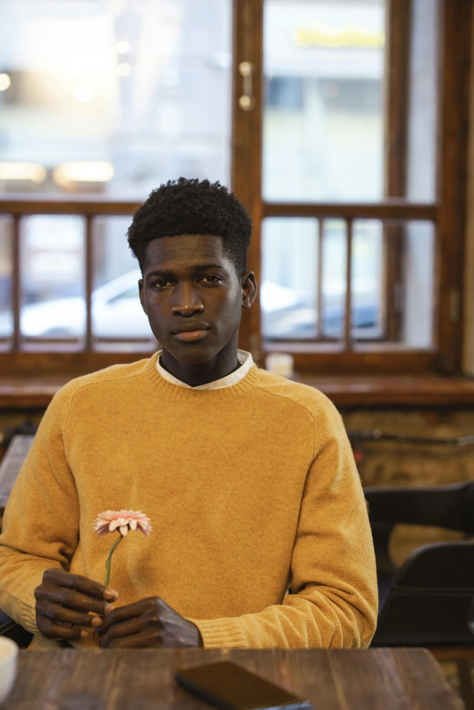 a man sitting at a table holding a flower