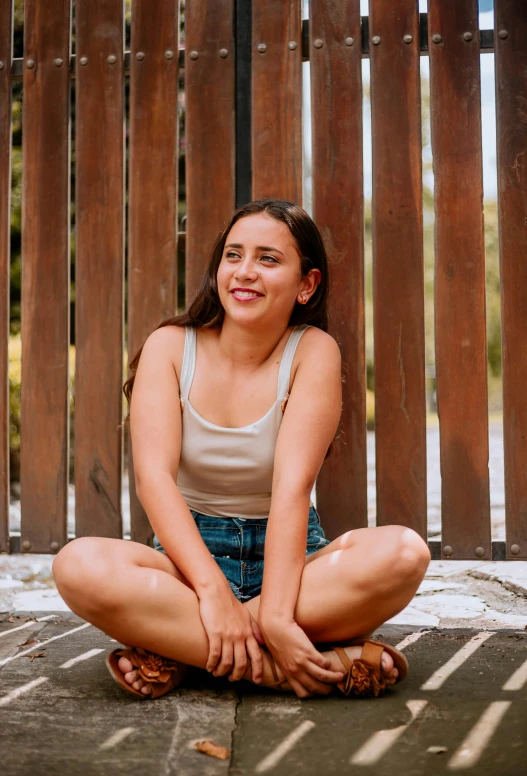 a woman sitting on the ground smiling while looking at camera