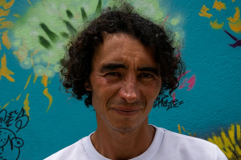 a young man standing next to a wall covered in graffitti