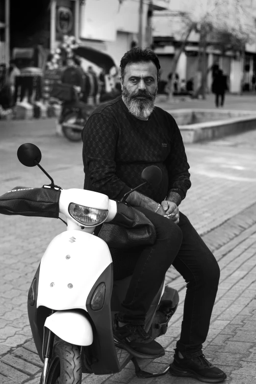 a man sits on top of a motor scooter