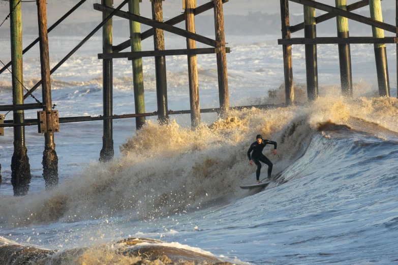 a surfer catching a wave under a dock