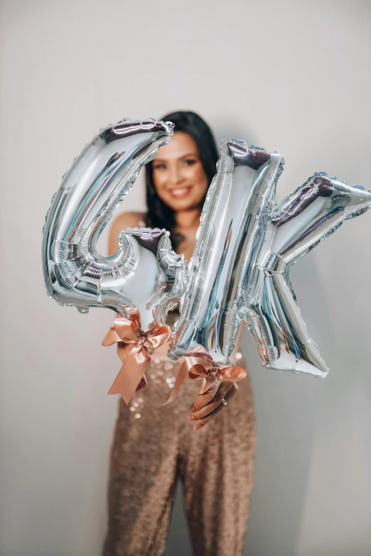 a woman holding up a large letter - k from an alphabet balloon