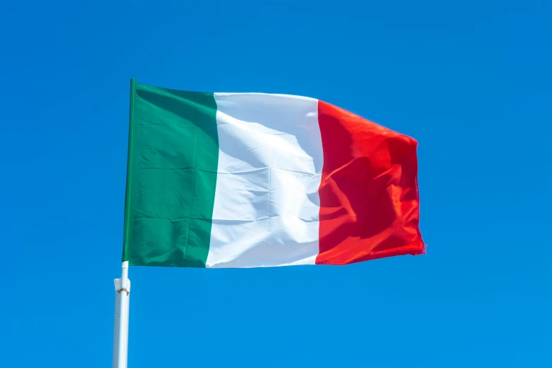 a large italian flag flying in the blue sky