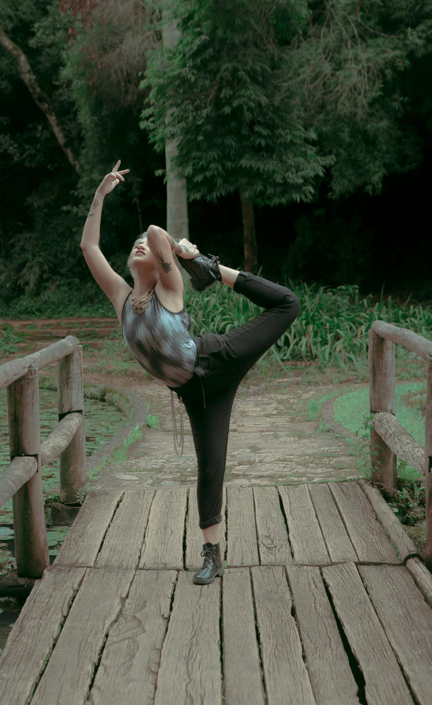 a woman stands on one leg on a bridge