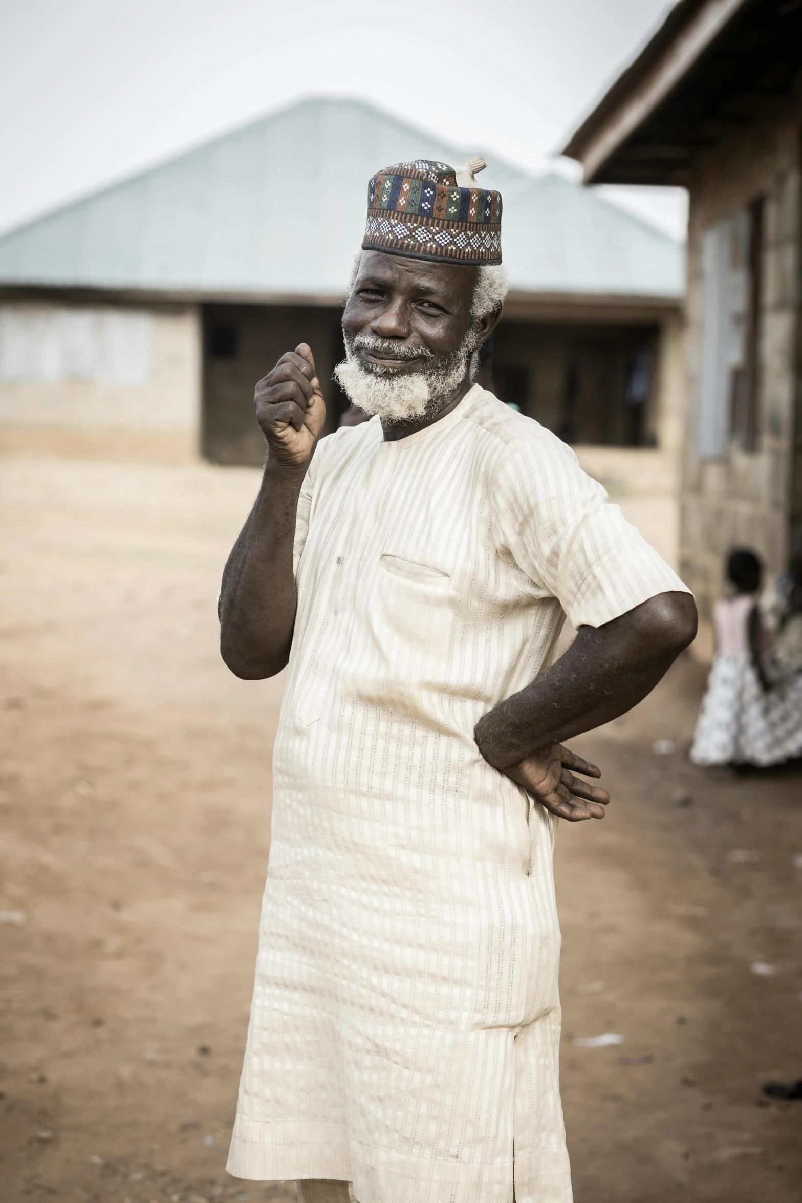 an older man standing in front of a house and holding a drink