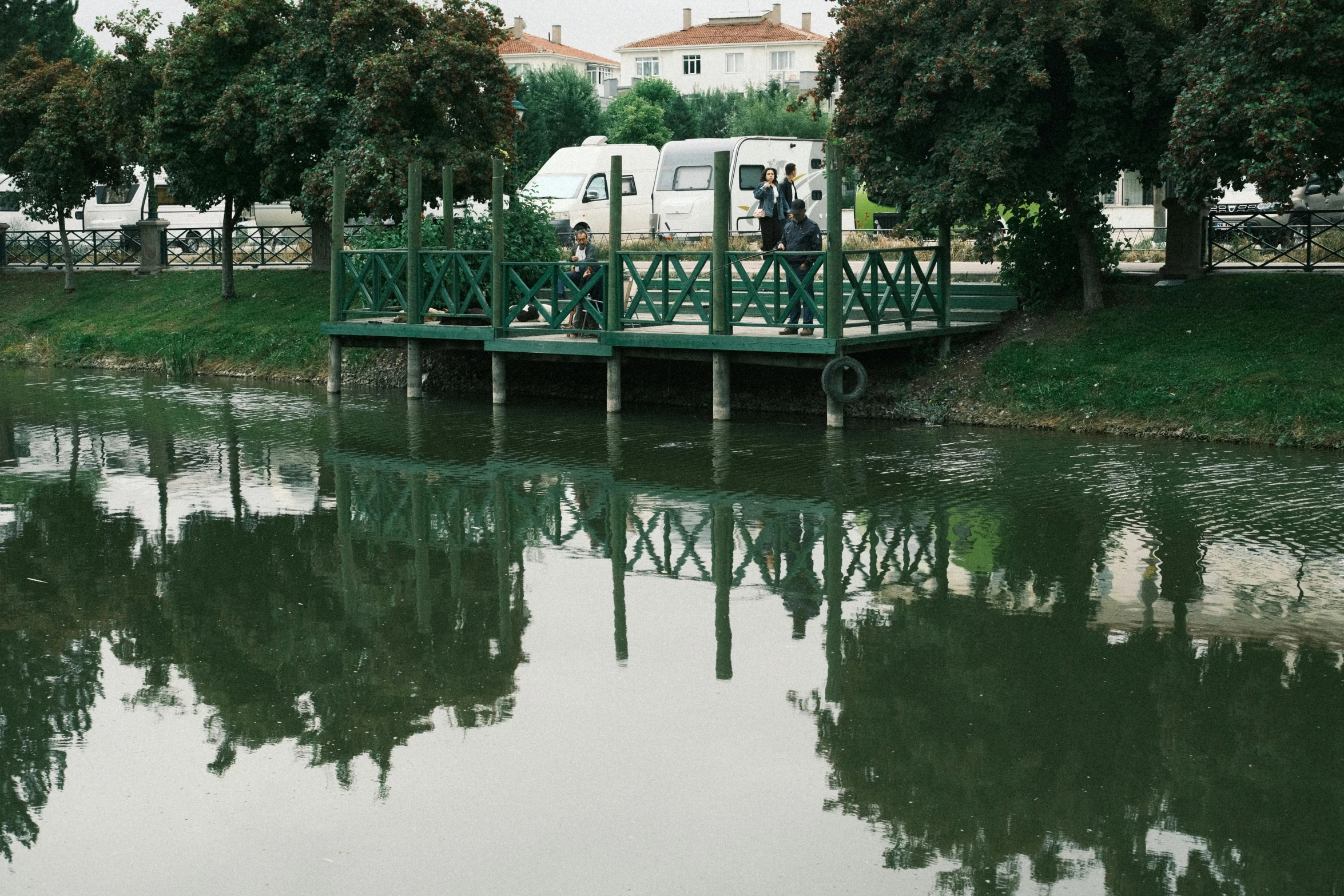 a small boat traveling across a lake next to a green bridge