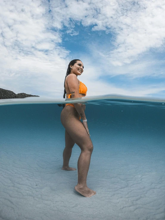 a woman with no panties is wearing an orange bikini under water