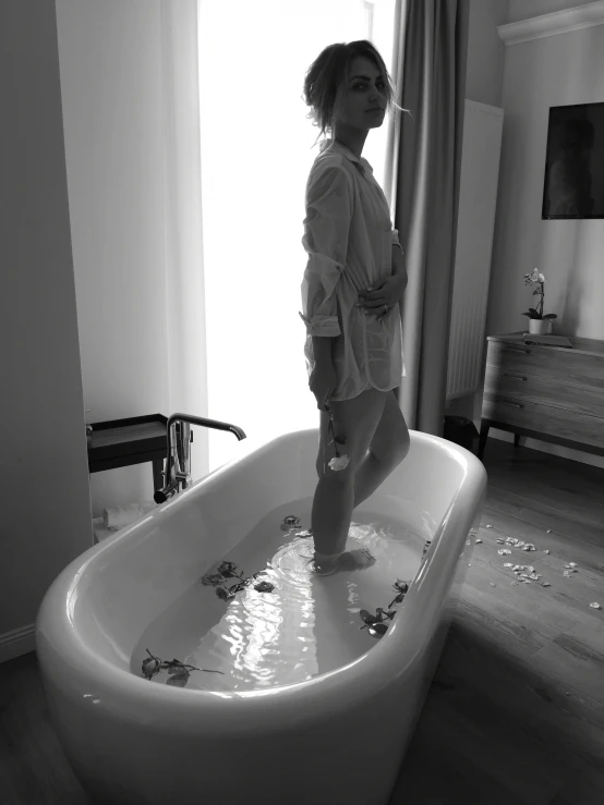 the girl is standing in a bathtub with petals in it