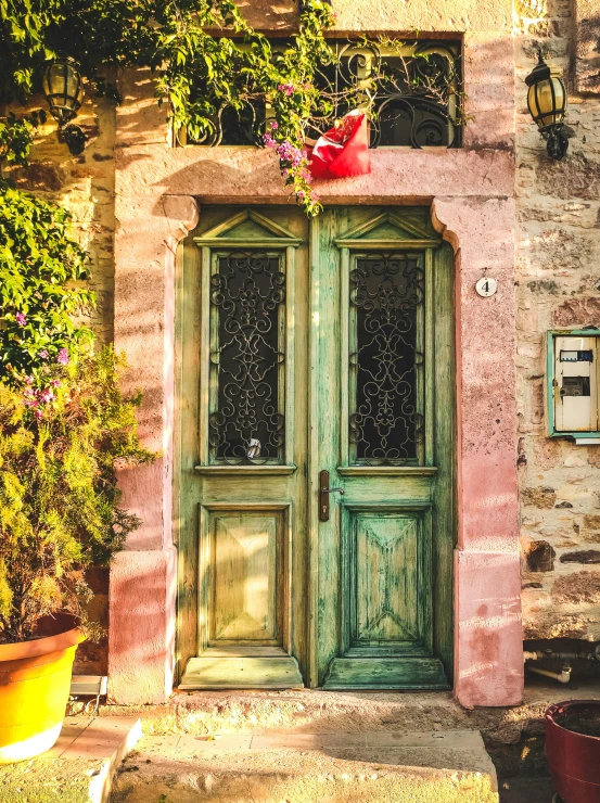 green wooden doors in front of old stone building