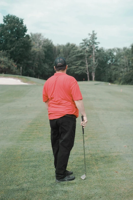 a man standing on top of a green golf course holding a golf club