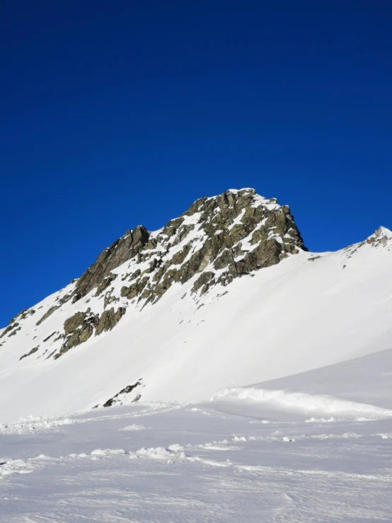 a snow - covered mountain with the top partially covered by deep blue skies