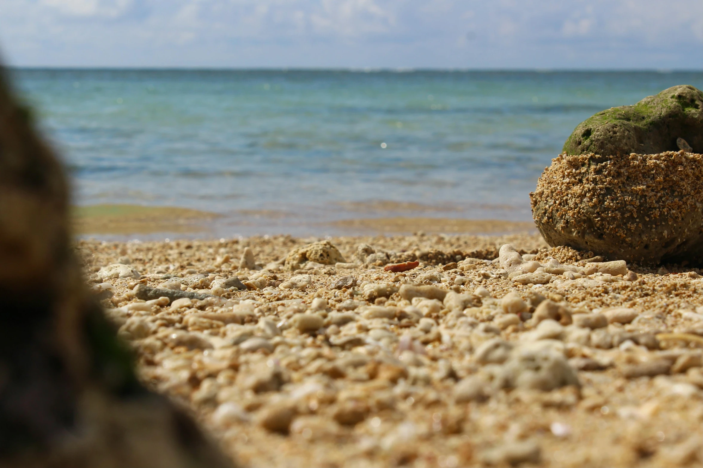 some sand rocks and water and blue sky