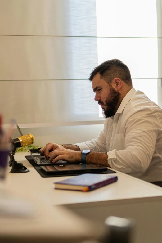 a man sits at a table working on a laptop computer