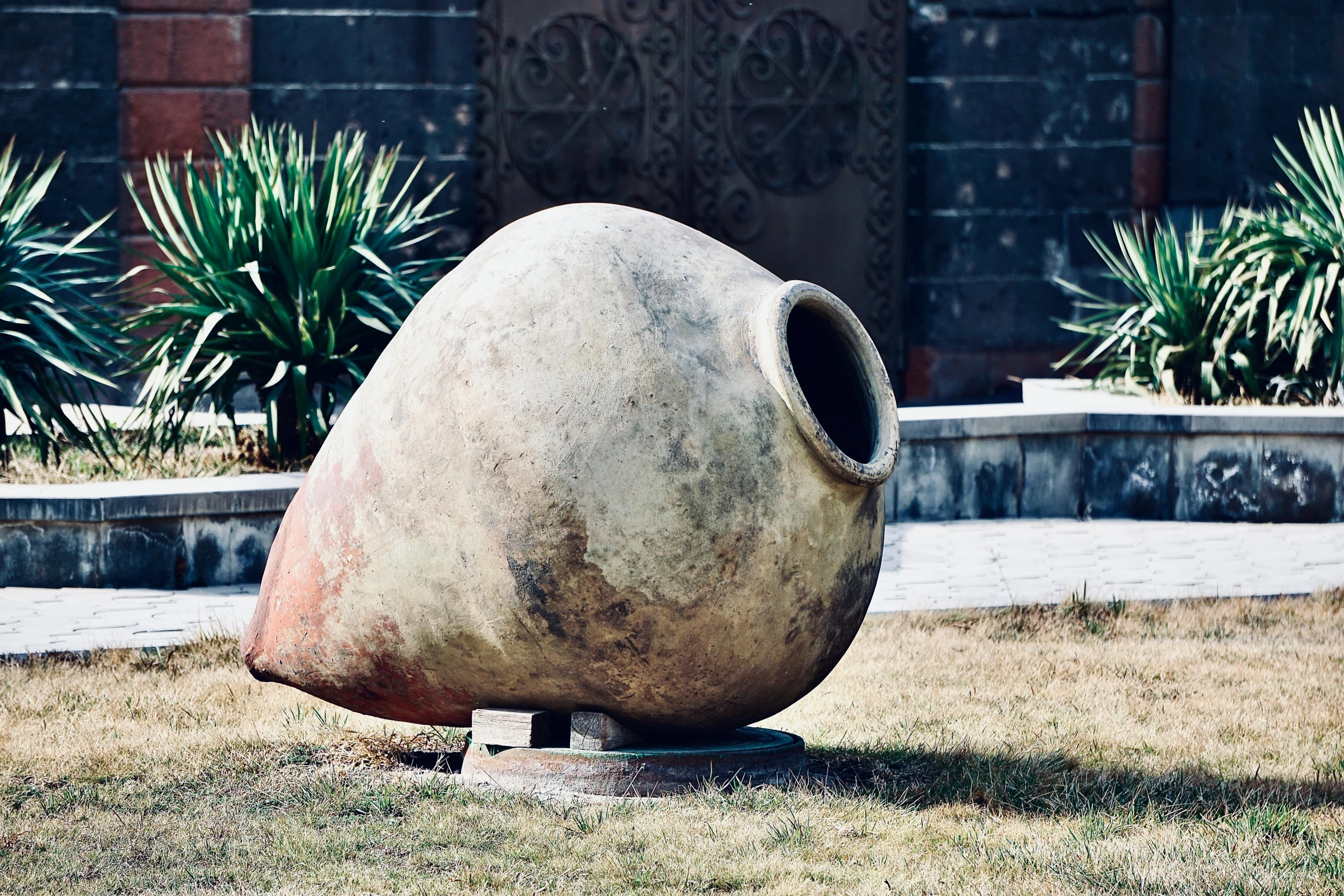 a large piece of clay sits in the grass outside of a building