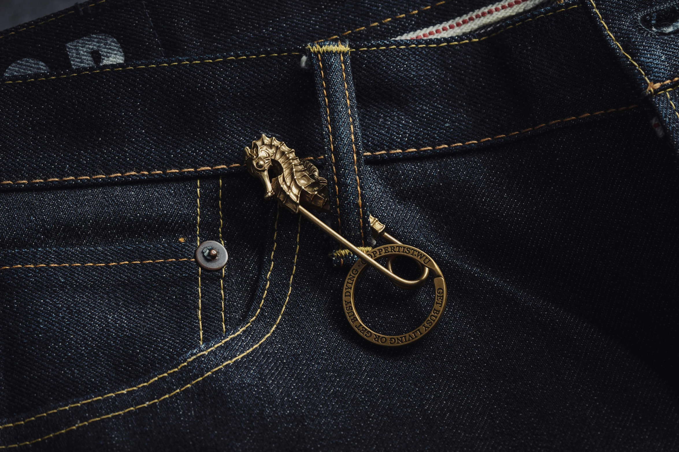 an odd shaped golden pin in the pocket of a pair of jeans