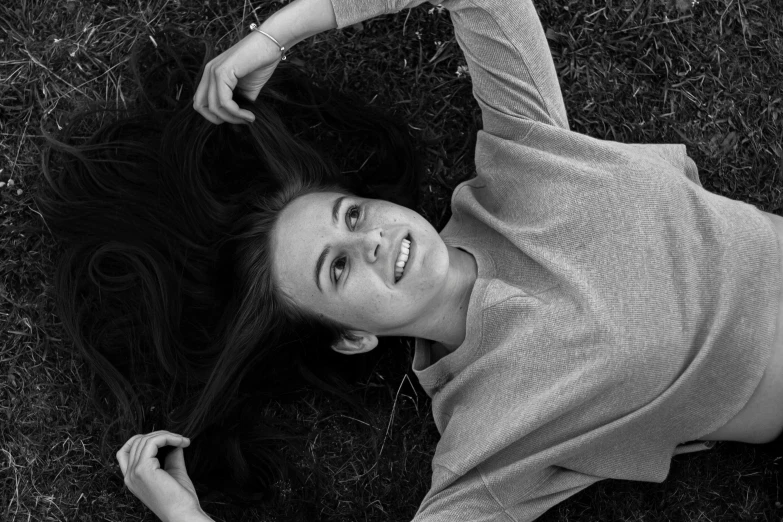 black and white po of a woman laying on grass