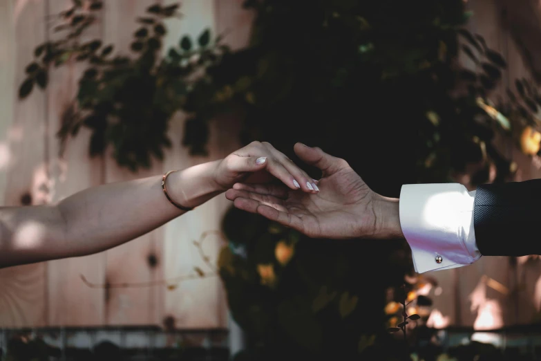 two people touching hands in front of a wooden wall