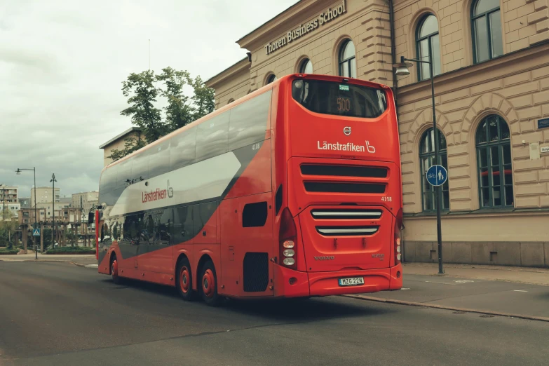 a red double decker bus stopped in front of a large building