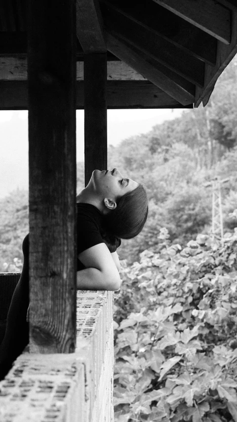 a woman is resting on a ledge, her face slightly covering her face