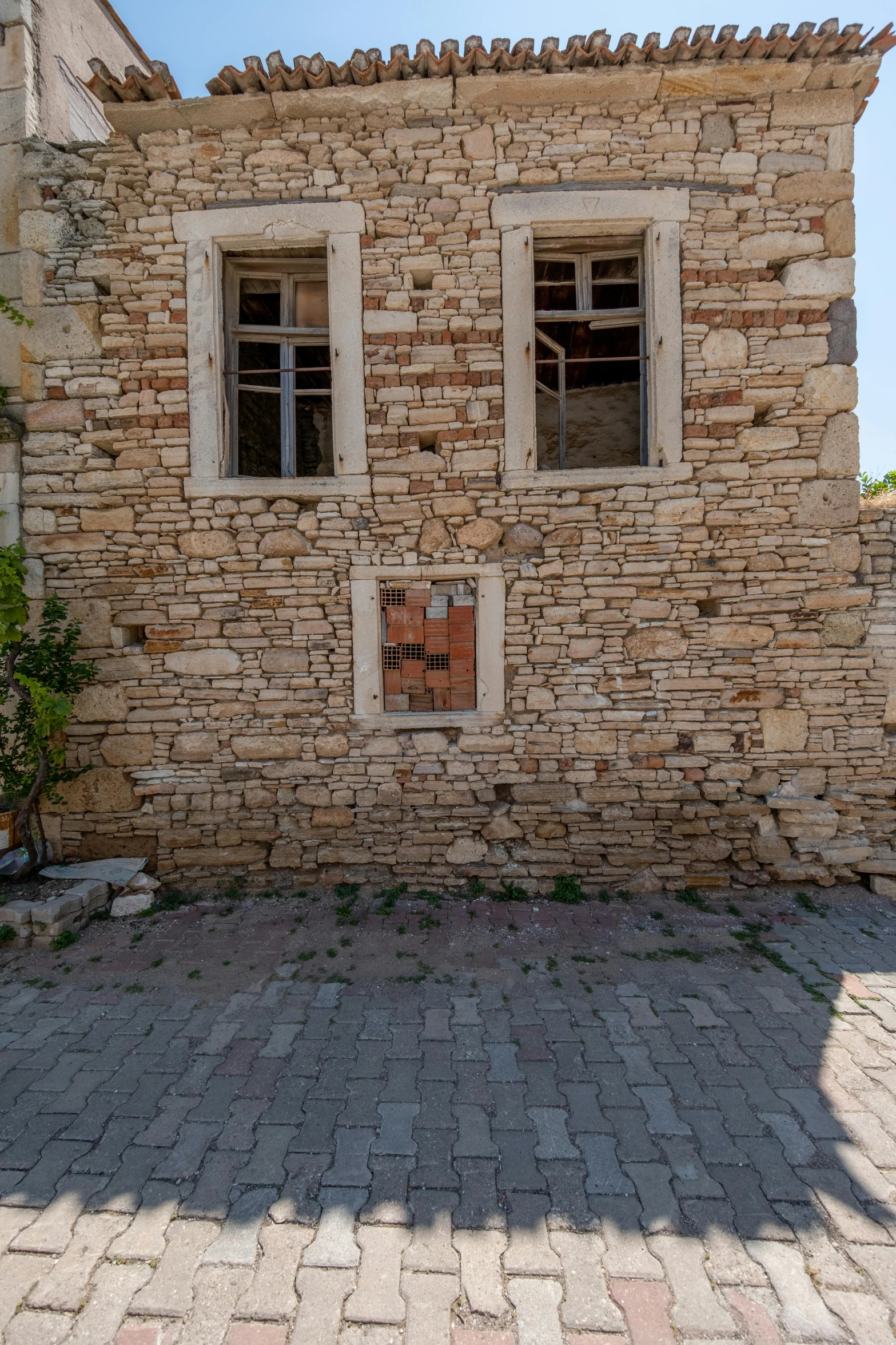 a stone building has two windows and a broken window