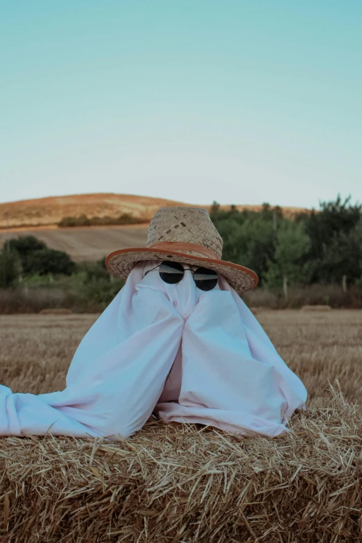 a person with a hat and sunglasses wrapped in blankets