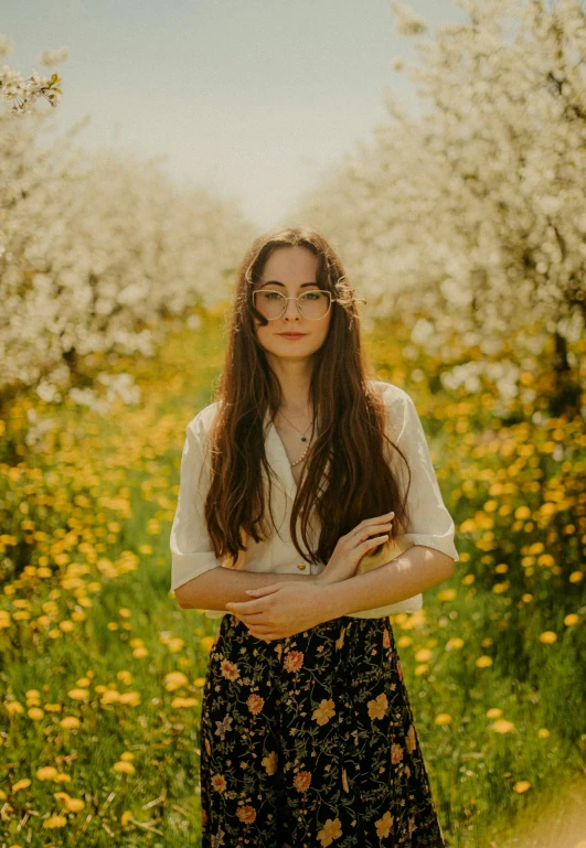 a young woman stands on the field in front of blooming flowers