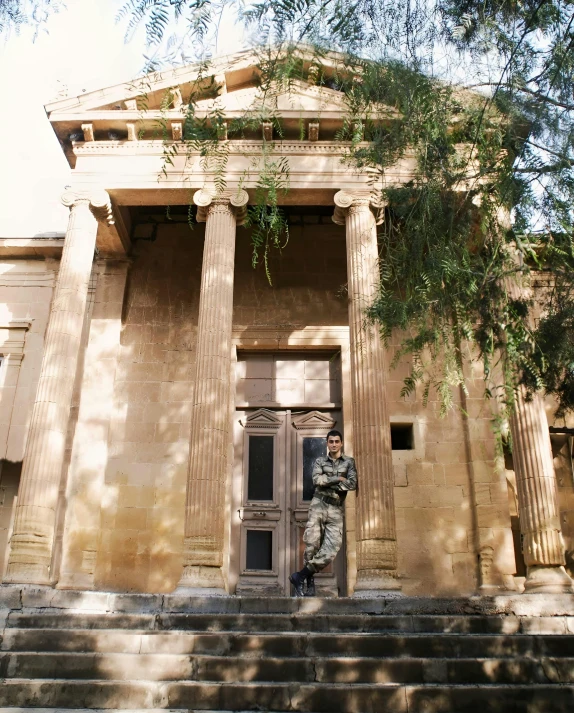 the man stands in front of a tall building that has two pillars