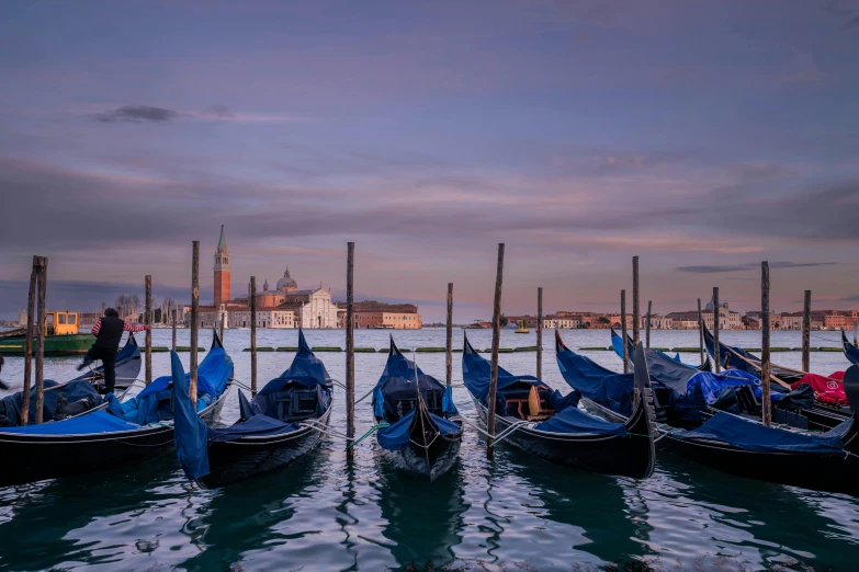 several gondolas lined up by poles in a body of water