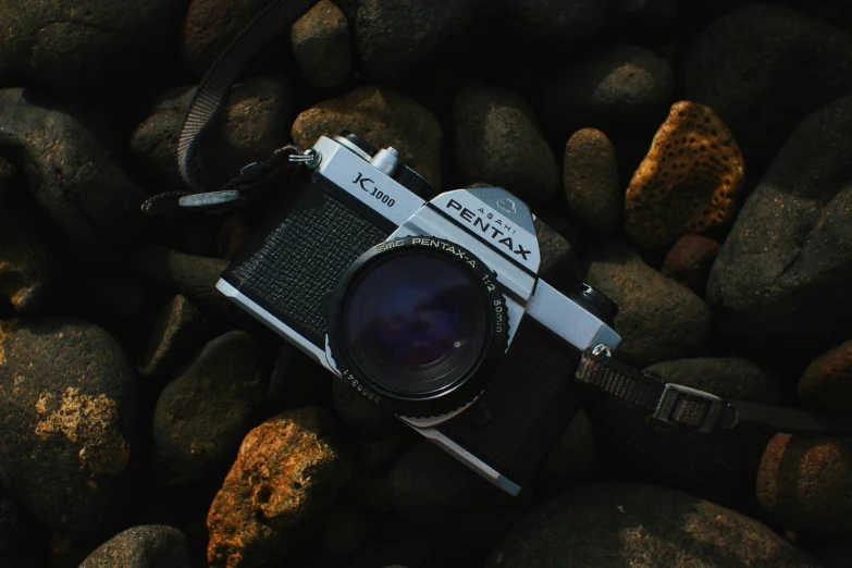 a camera laying on top of rocks with a lens attached to the front