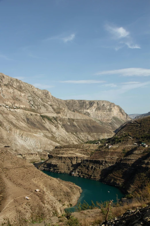 two goats are on the hillside near a lake