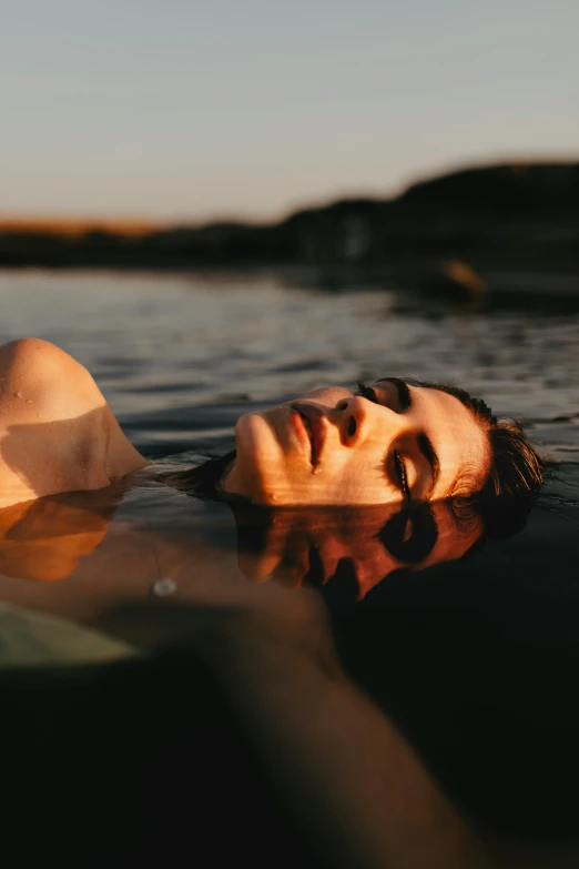 a man laying in water with his head above the surface