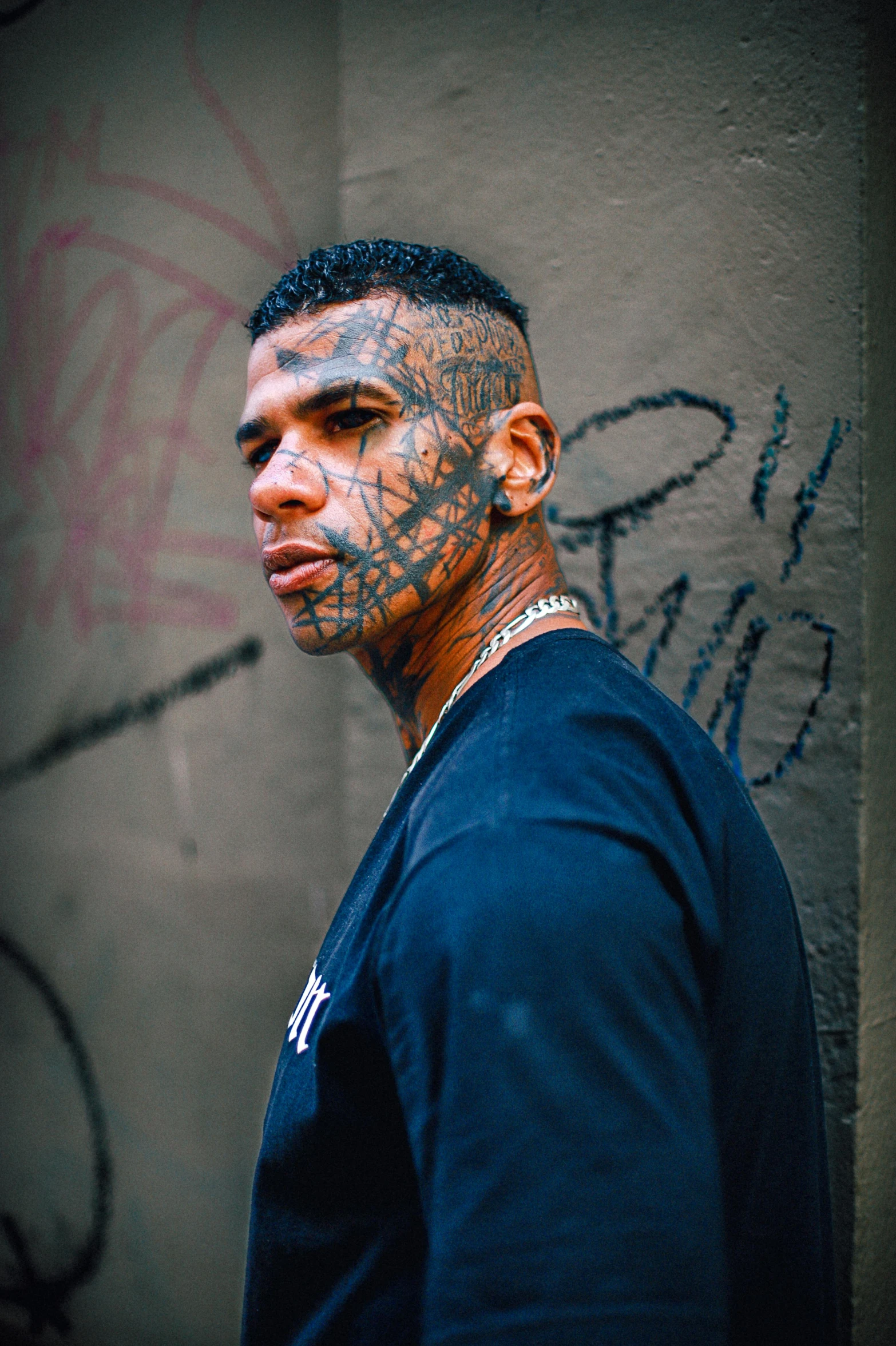 a man standing in front of a wall with graffiti