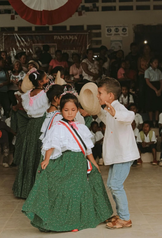 several children in long dresses and tiaras perform a dance