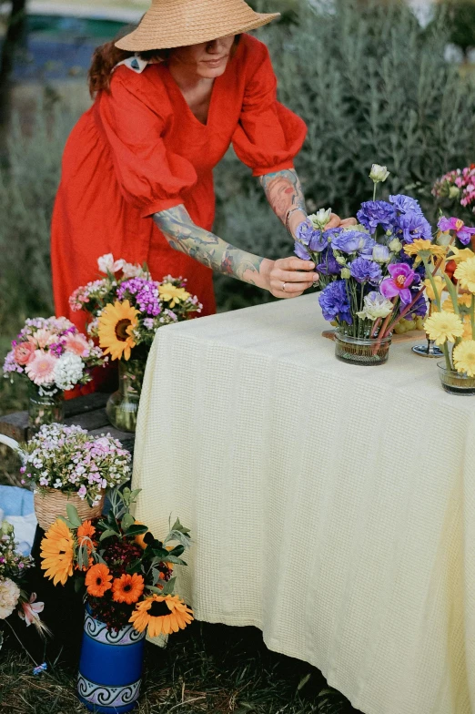 a woman is arranging flowers on an outdoor table