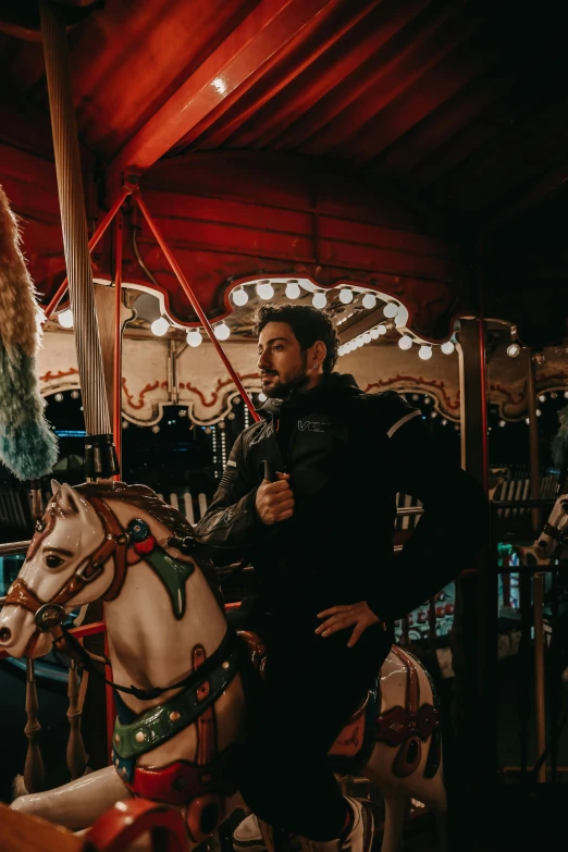 a man with beard standing on a merry go round horse