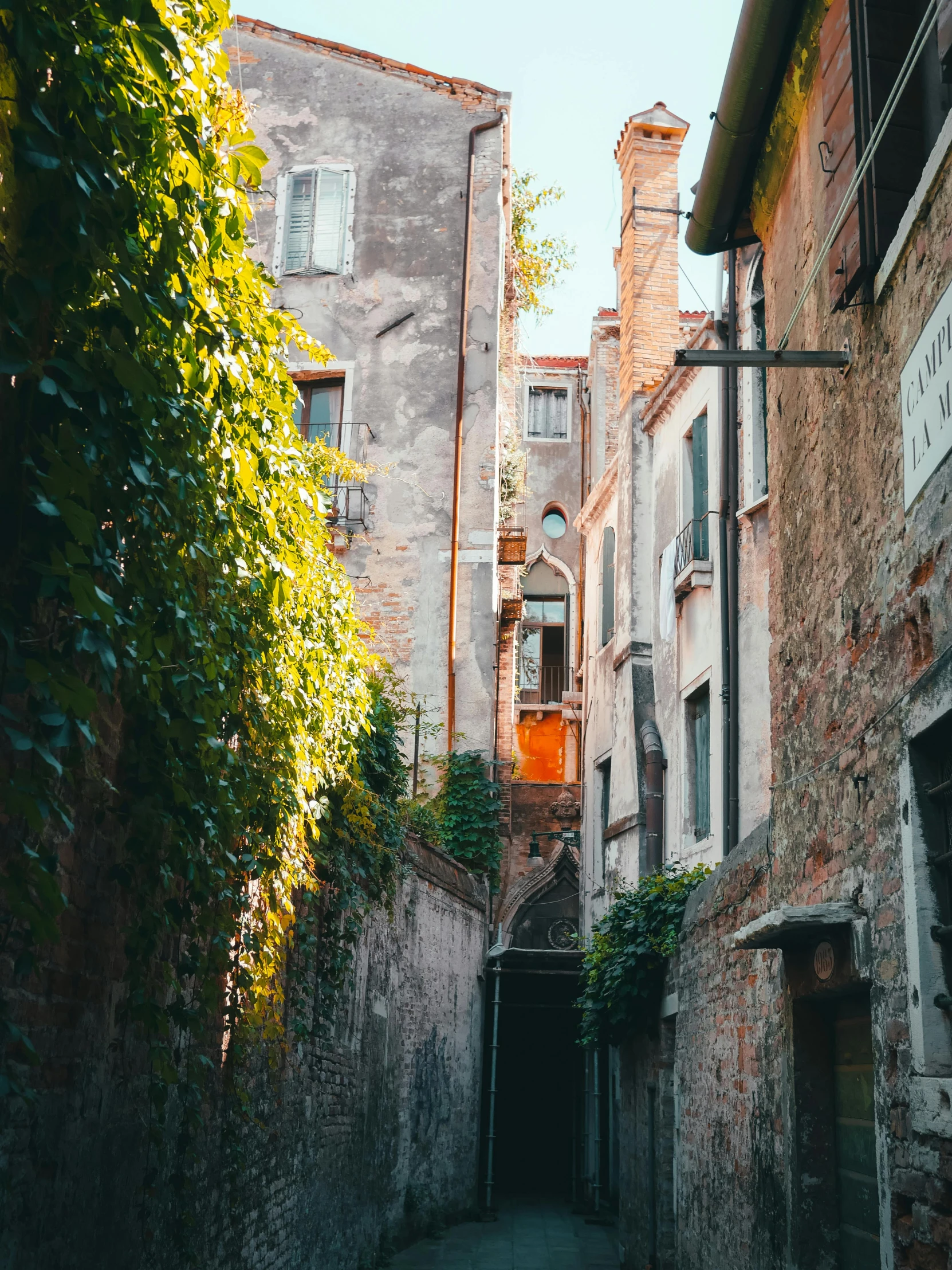 a narrow road leading to a stone building with a clock on it